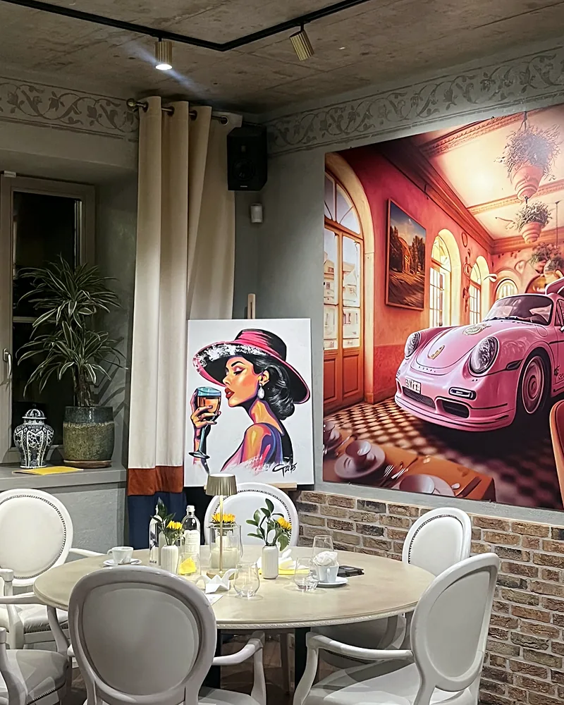 Salės kampas su paveikslu, kuriame pavaizduotas rožinis Porsche